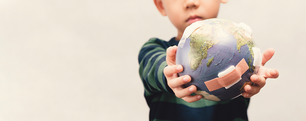 Ein Kind hält eine Weltkugel vor sich in den Händen.